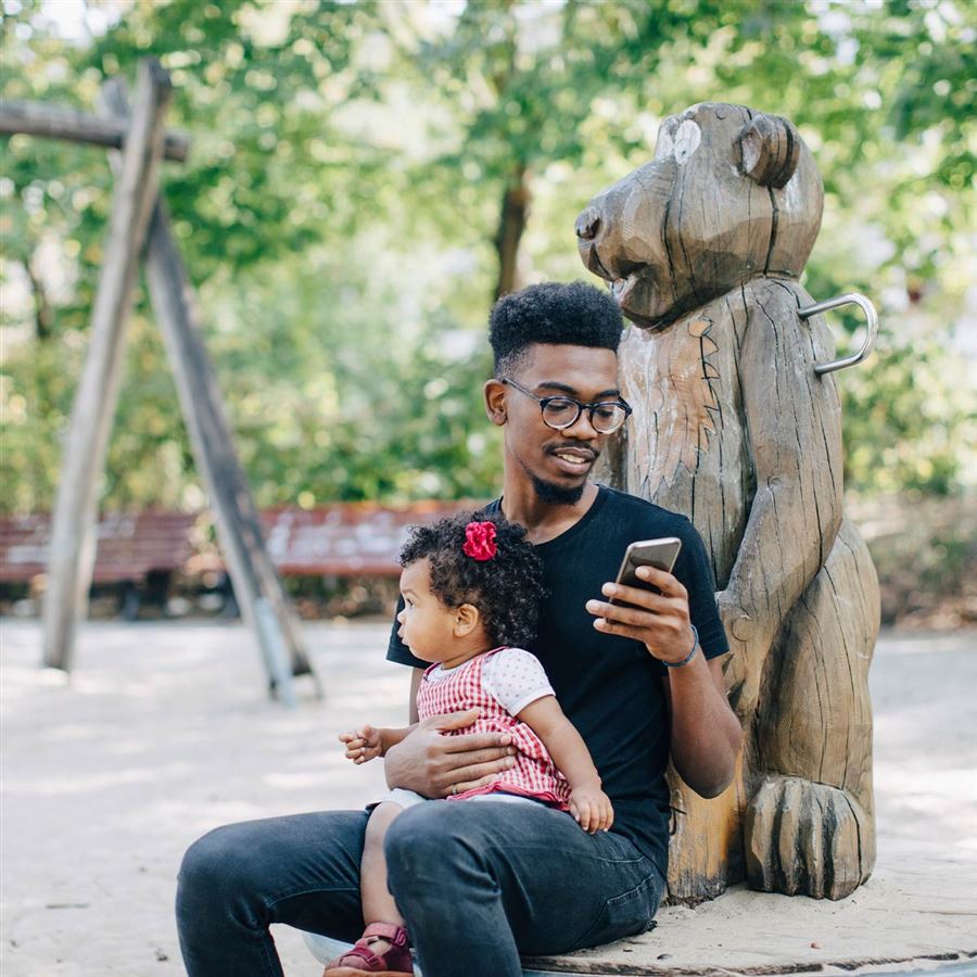 En pappa med sin dotter på en lekplats.