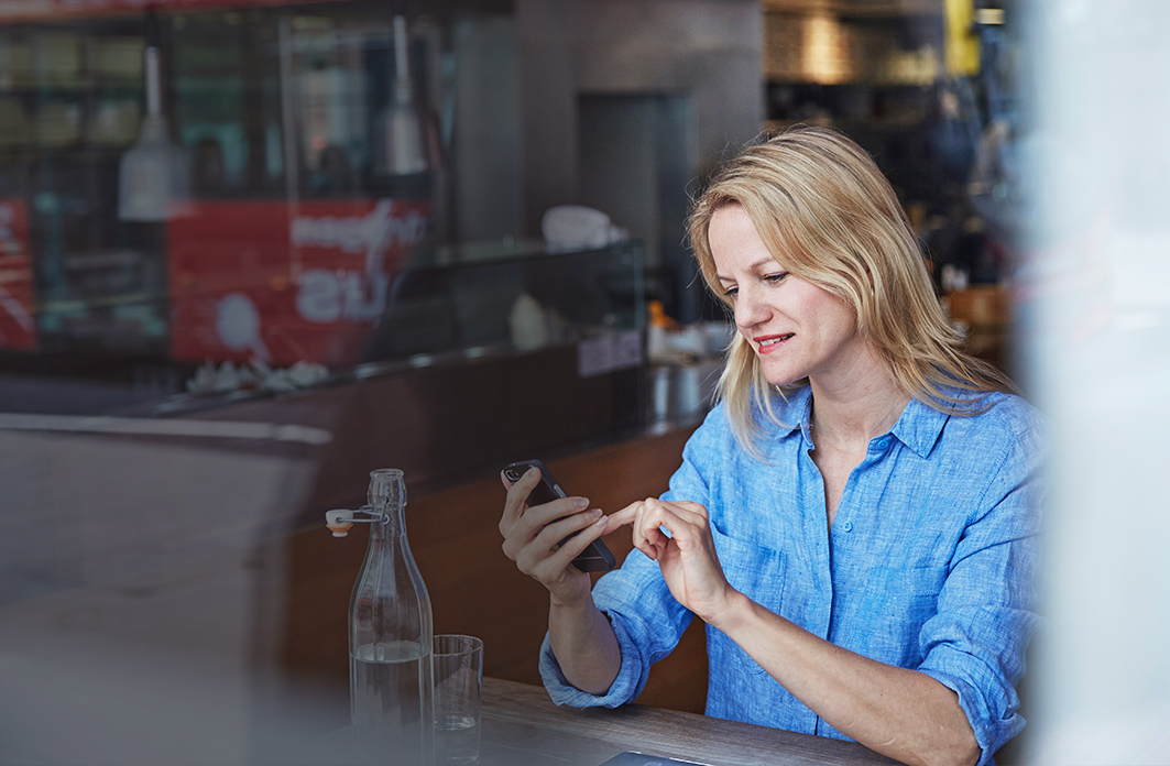 a woman sitting by a table looking at her mobile