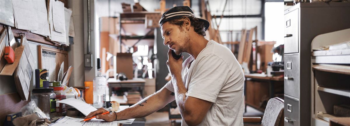 En man i byggbranschen kontrollerar en order och pratar i telefon
