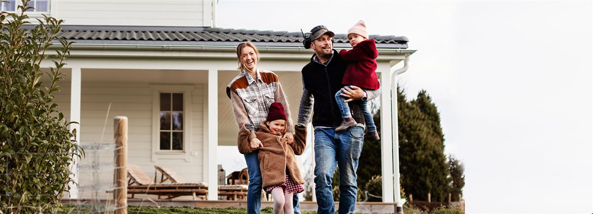 En ung familj som utanför sitt hus på landet.