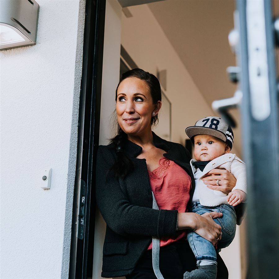 Mamma med barn på höften står i dörröppning