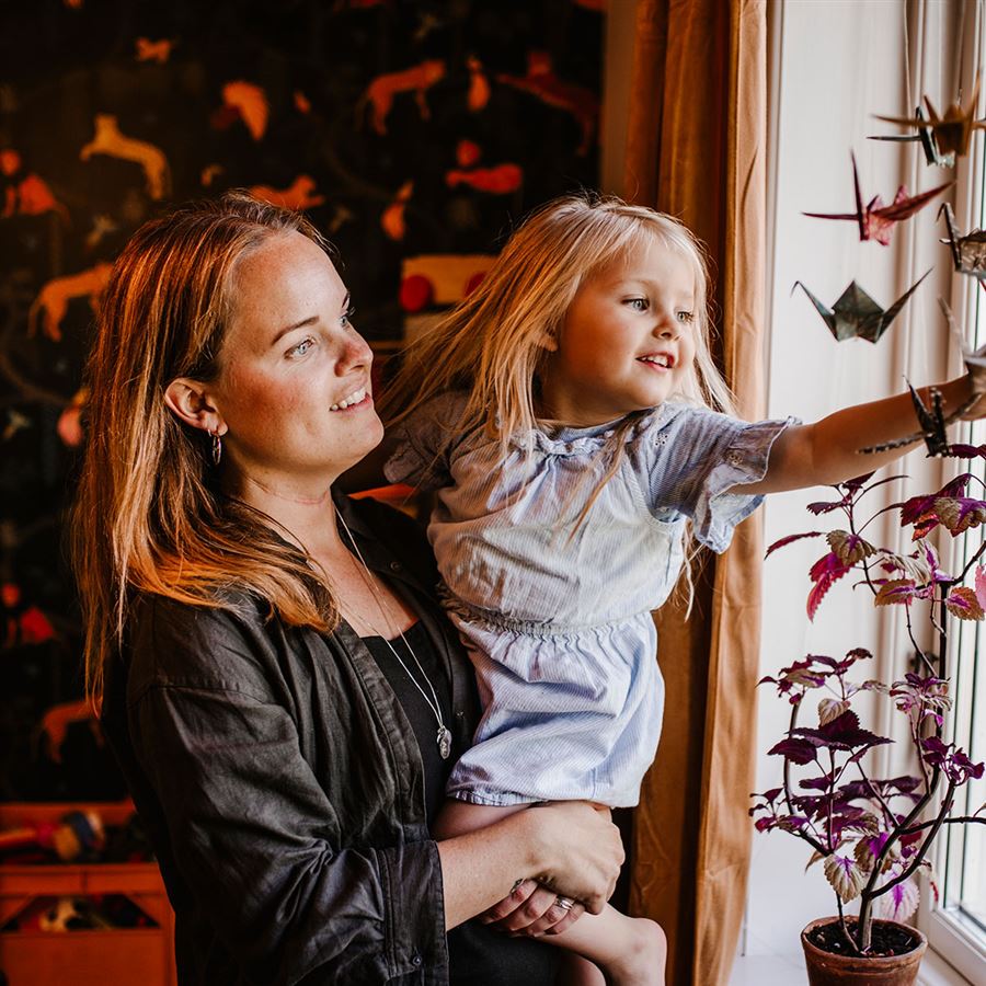 En mamma med sin dotter tittar ut genom fönstret. 