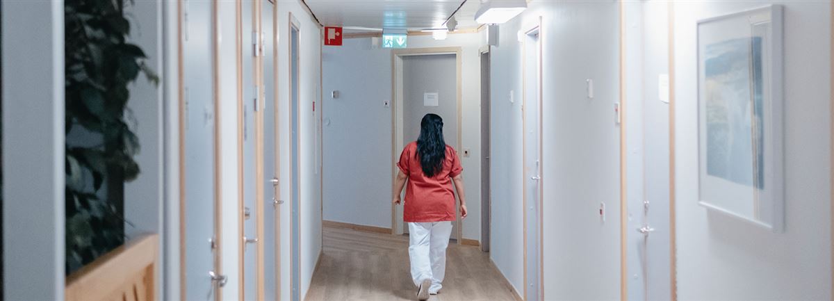 Ett vårdbiträde går i en korridor på ett sjukhus