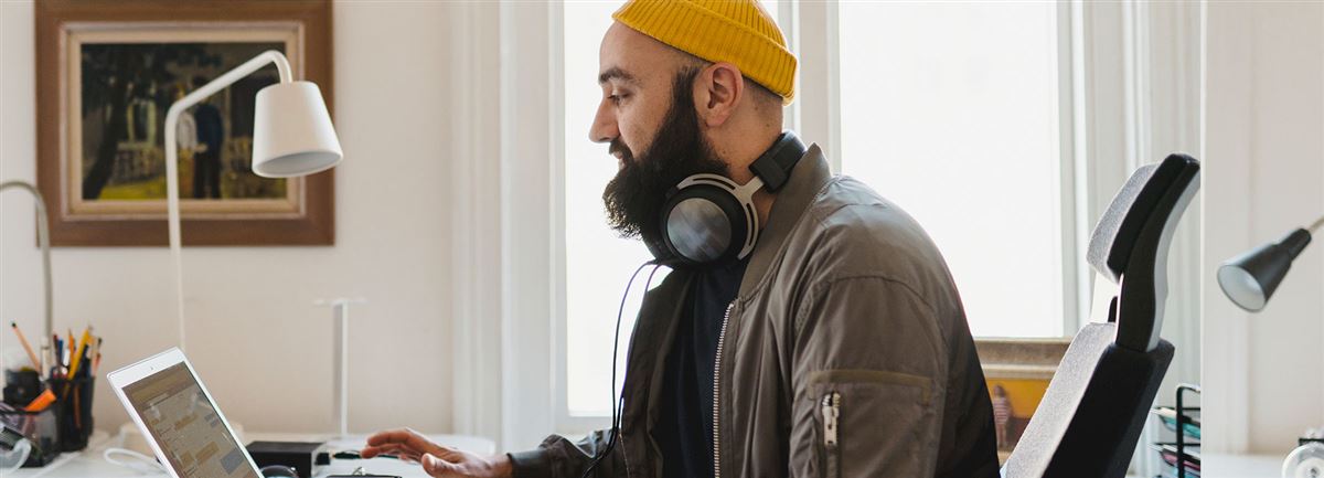 Man med gul mössa som sitter vid sin dator och arbetar