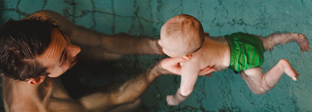 En pappa badar tillsammans med sin bebis i en pool.