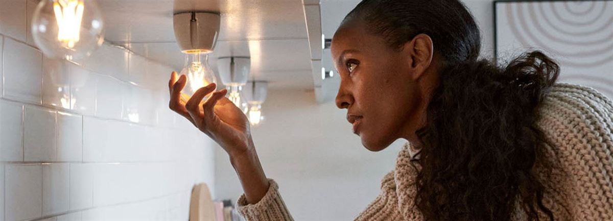 Kvinna i kök med tända lampor. Foto:Vattenfall