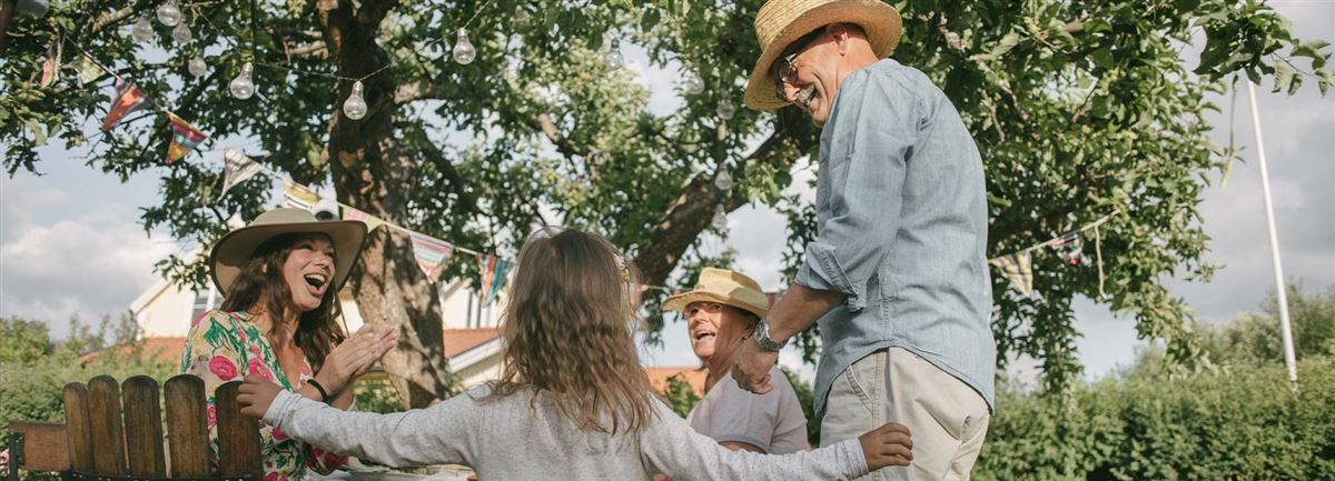 En barnfamilj är i sin trädgård på sommaren