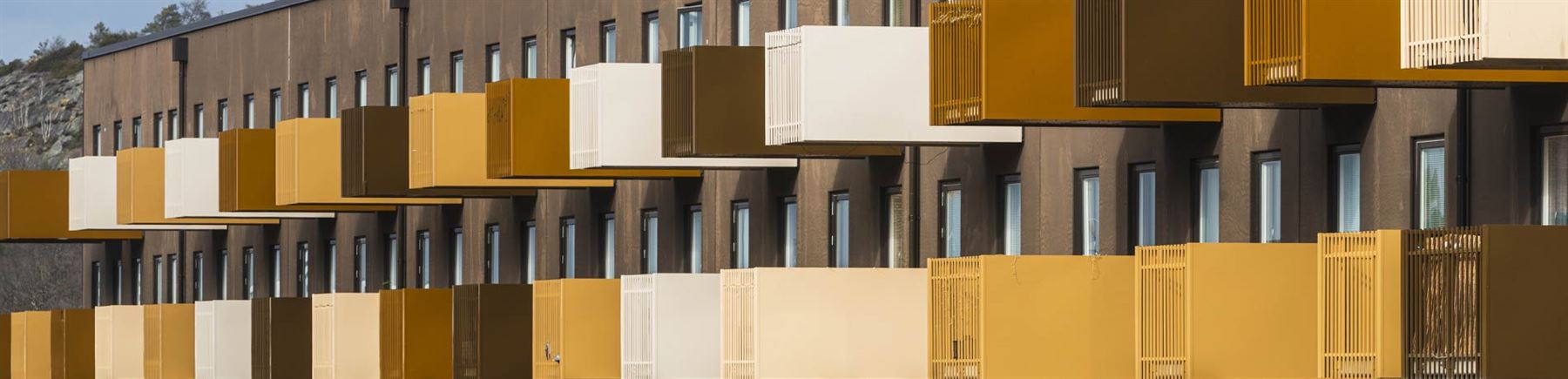 Ett fasad på ett bostadshus med balkonger i olika färger.