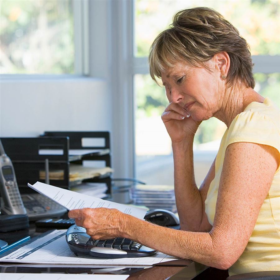 En kvinna som sitter framför sin dator med en faktura i handen.