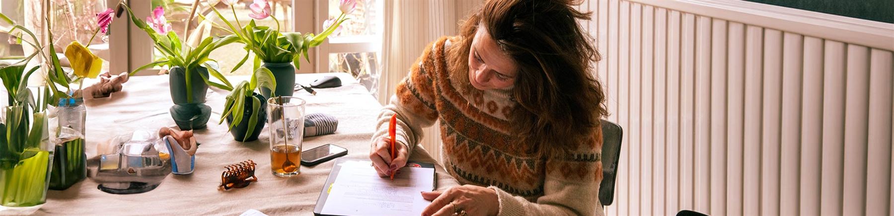 Kvinna sitter vid bord och räknar ut kostnader