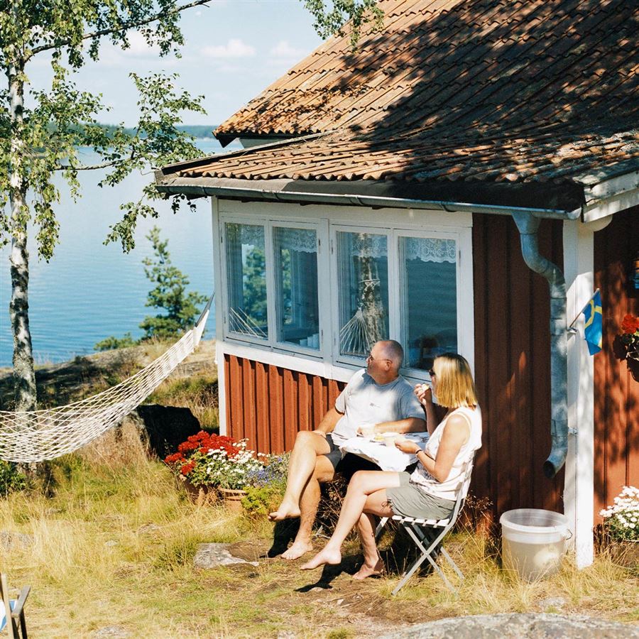 Par sitter framför sin sommarstuga
