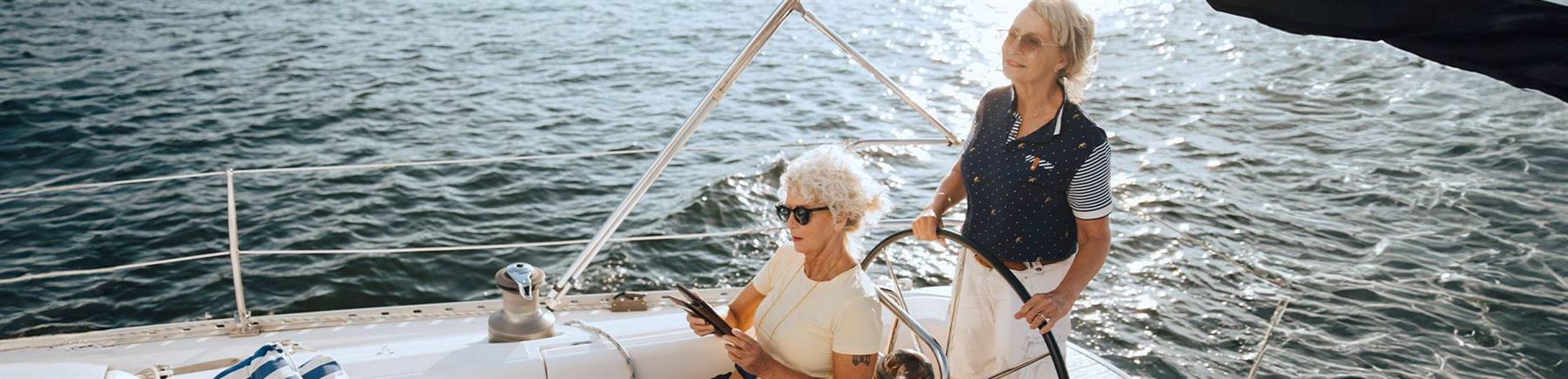 Två äldre kvinnor i en segelbåt på havet.