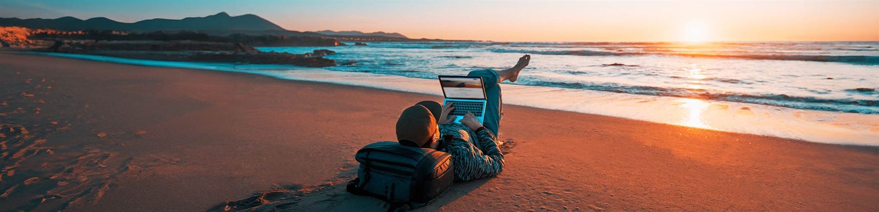 Man läser på sin dator på stranden.