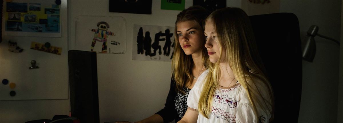 Två tonårsflickor sitter vid datorn. 