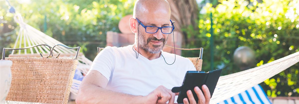 Man sitter en trädgård och tittar på sin telefon