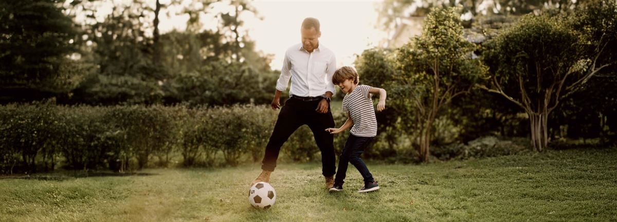 Pappa och son spelar fotboll.