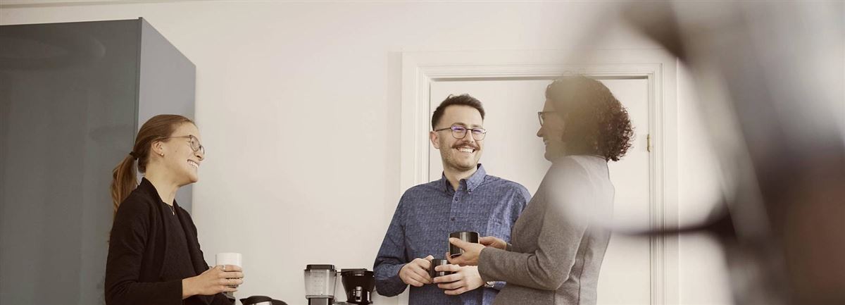 Kollegor diskuterar försäkringar över en kopp kaffe.