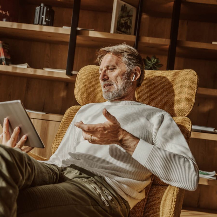 Äldre man i fåtölj med surfplatta.
