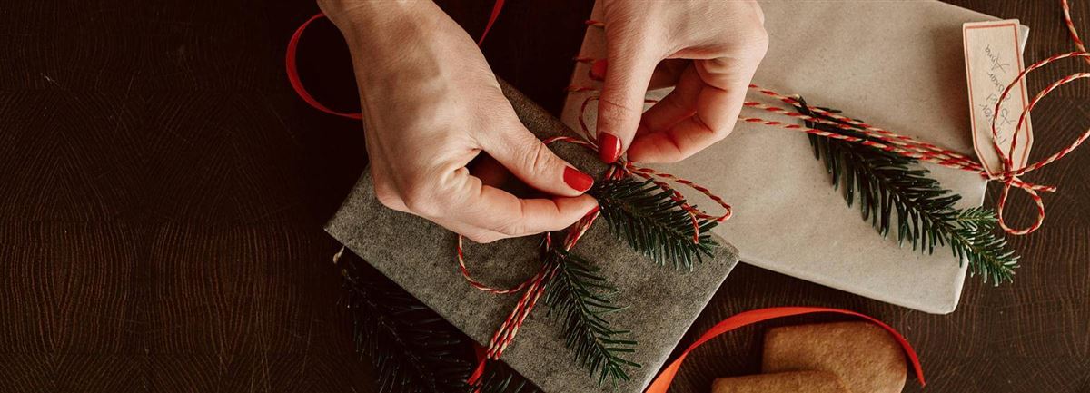 Händer som slår in julklapp.
