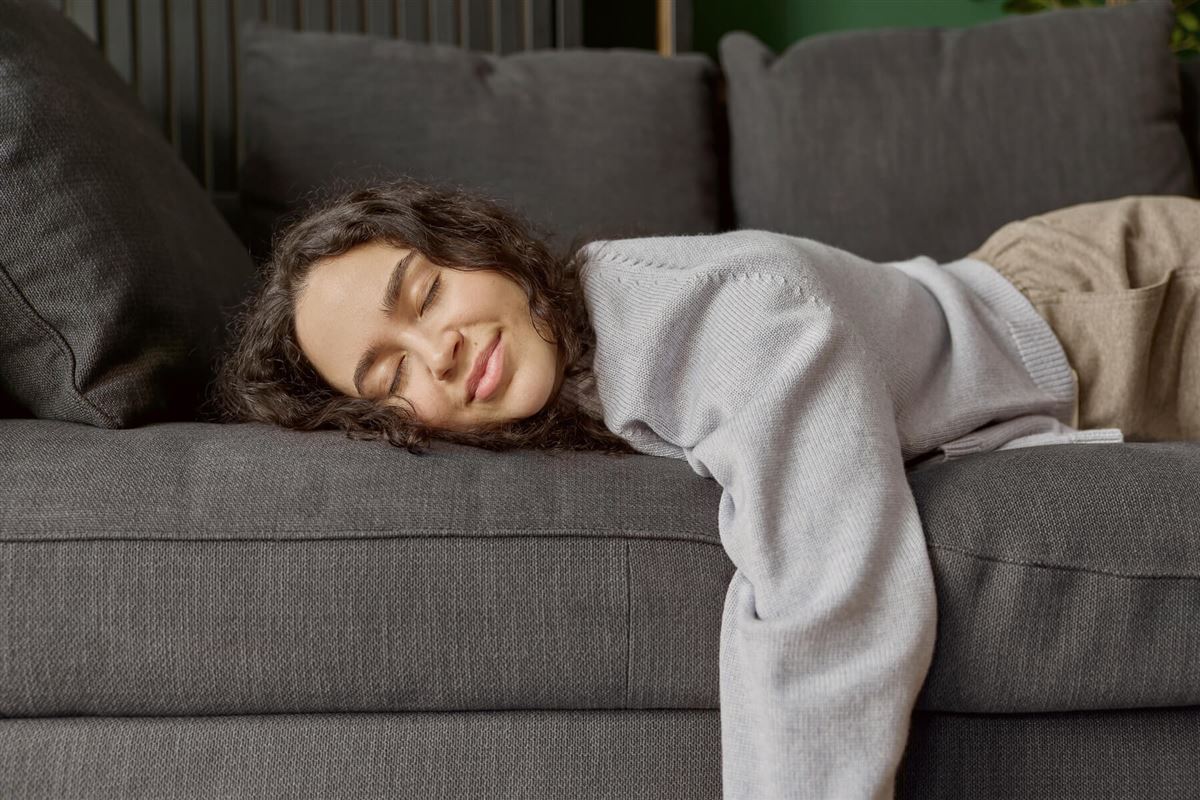 Kvinna ligger och vilar i sin soffa.