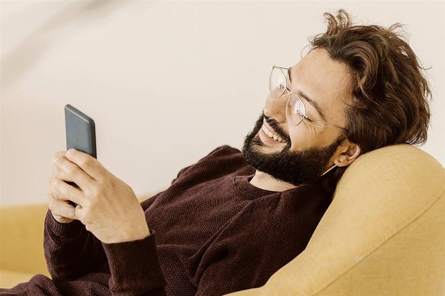 Leende man kollar i sin mobiltelefon.