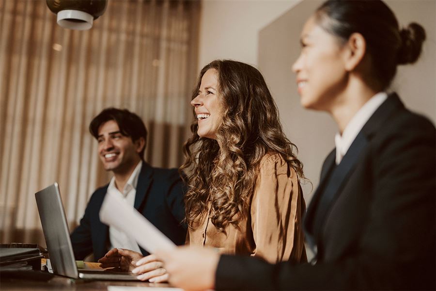 Skrattande kollegor i ett mötesrum.