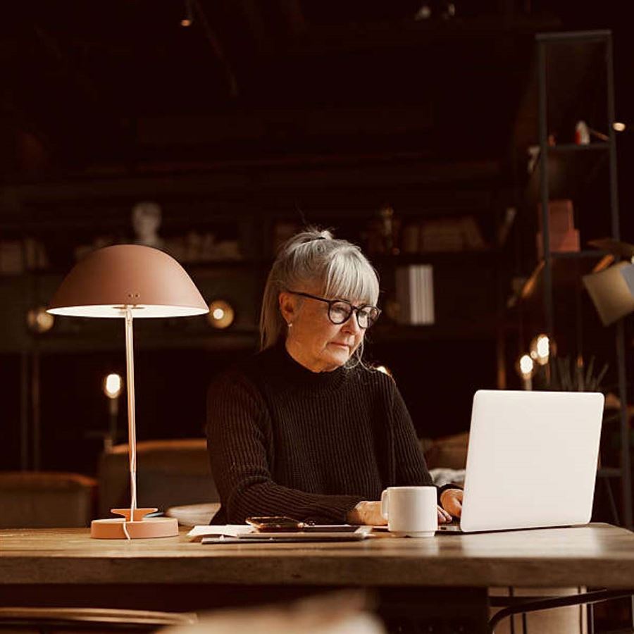 Kvinna kollar fonder framför dator.