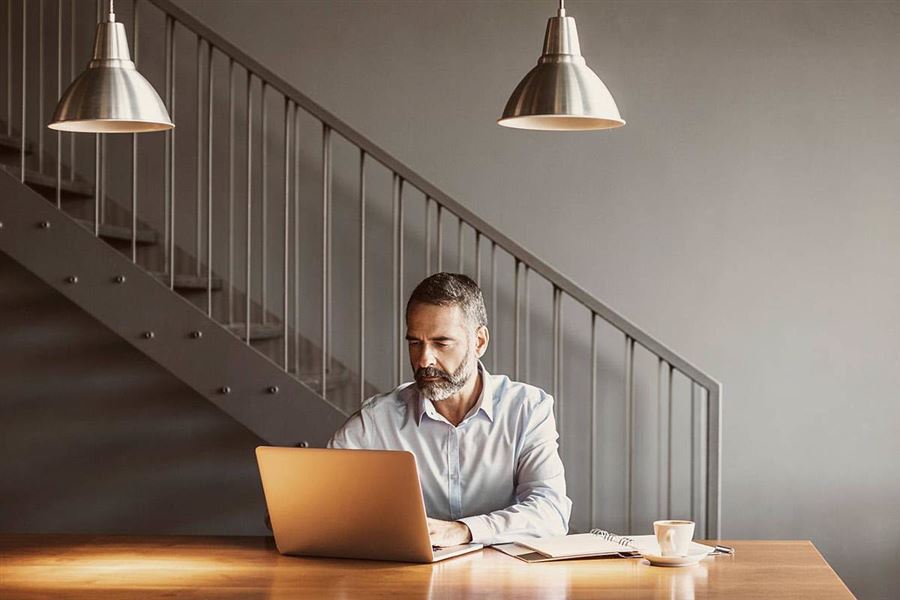 Man sitter vid ett bord med en laptop.