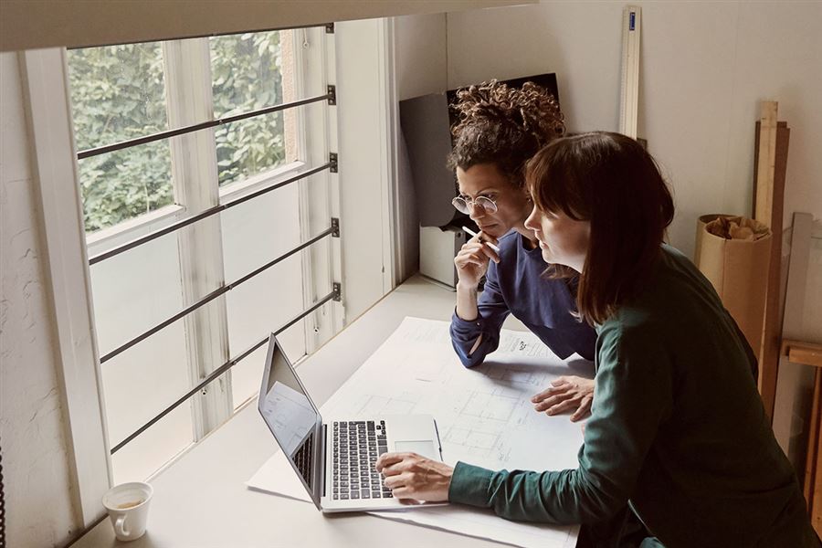 Två kvinnliga arkitekter arbetar med en ritning.