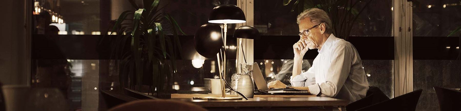 Äldre man kollar sitt sparande på dator.