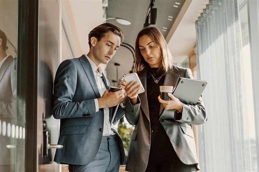 Två kollegor läser om Swish återkommande betalningar.