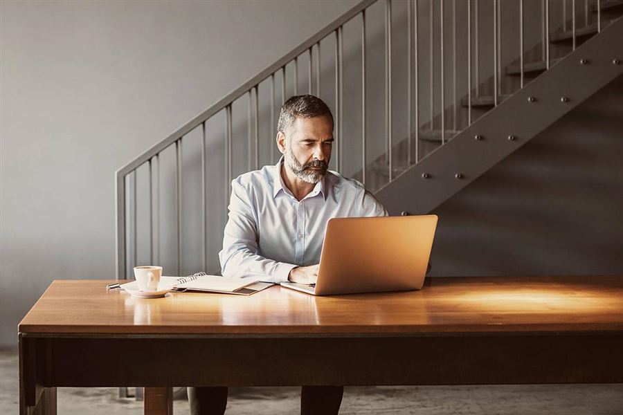 En man sitter framför sin laptop.