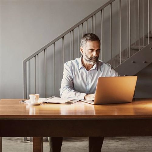 En man sitter och arbetar framför en laptop.