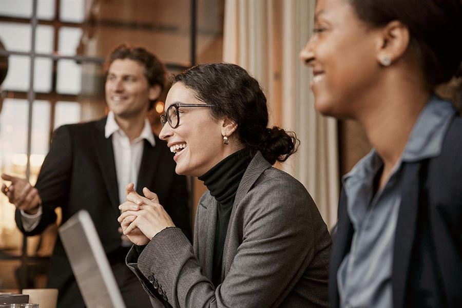 Glada kollegor sitter vid ett bord och samtalar. 