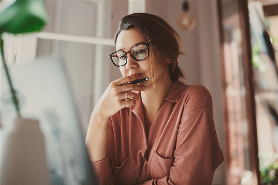 Kvinna funderar framför sin dator.