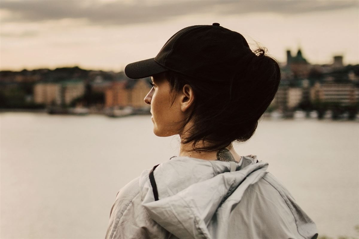 Kvinna står och ser ut över vattnet och staden. Hon funderar över vilket sparkonto hon ska öppna. 