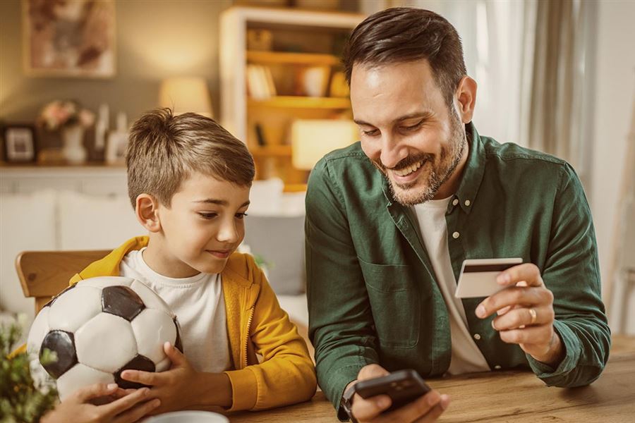 Pappa visar son hur Swish fungerar på sin mobil.