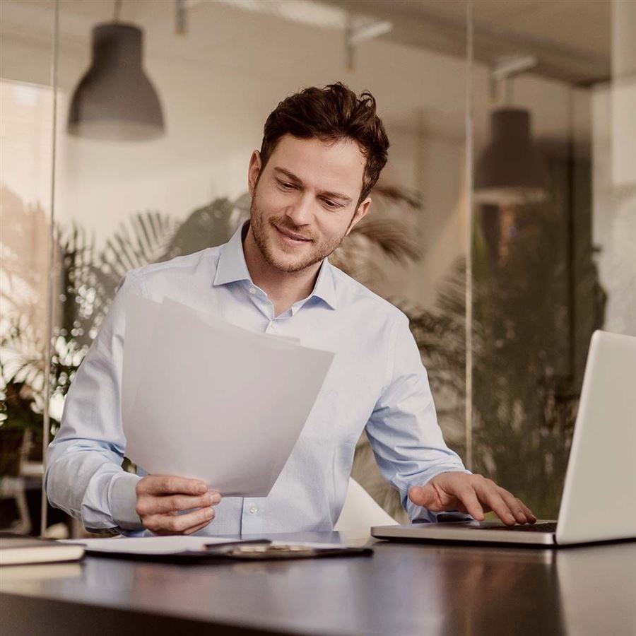 En egenföretagare sitter framför sin dator i en kontorsmiljö.