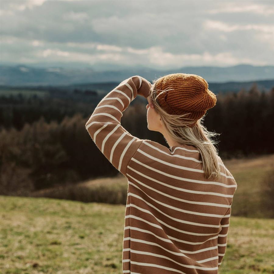Kvinna blickar ut över ett skogslandskap i samband med skogsägande och skogens ekonomi.
