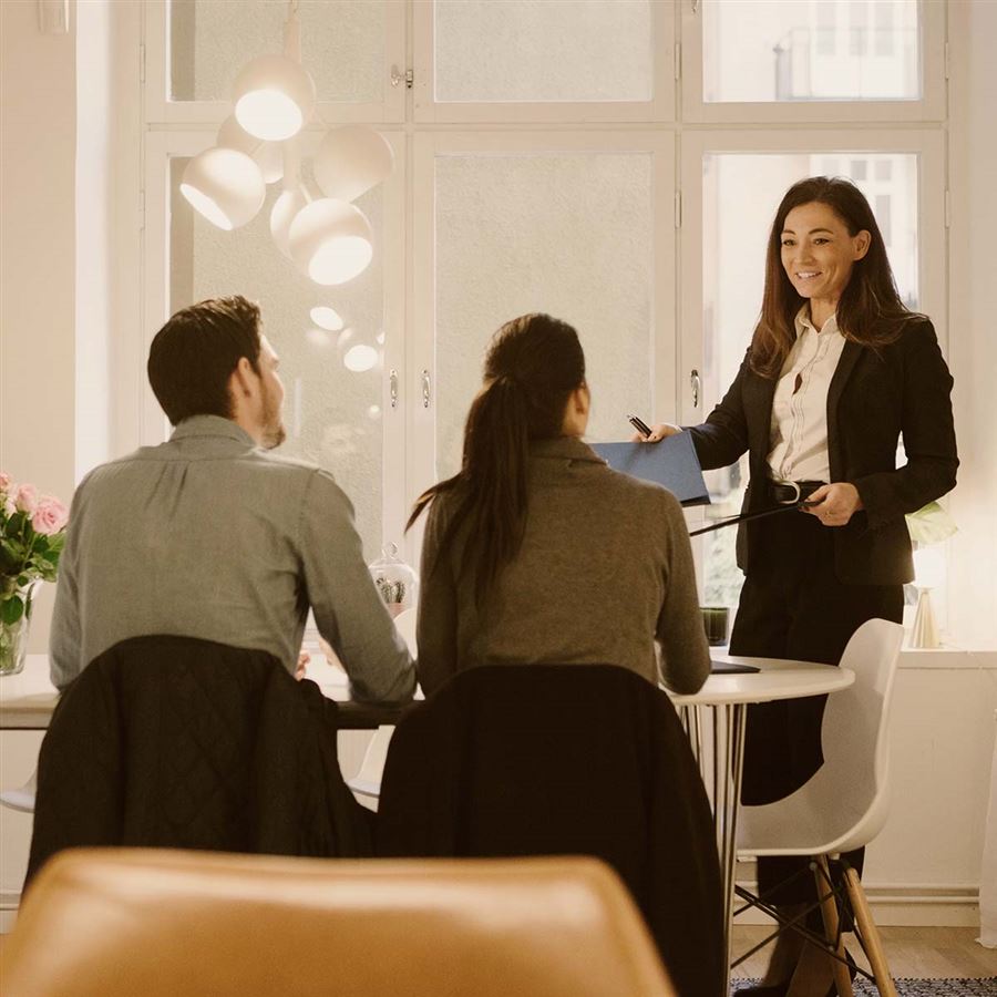 Tre personer i möte pratar bostadspriser.