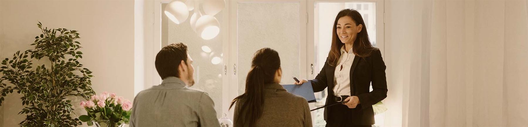 Tre person i ett rum inför kontraktskrivning till ny bostad.