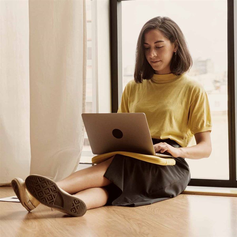 En kvinna med en laptop i sitt knä.