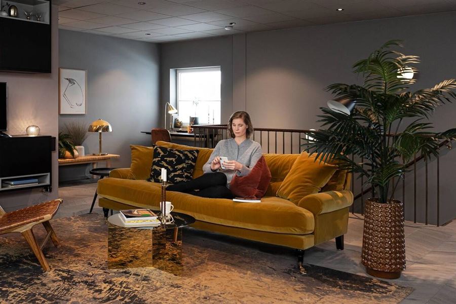 Kvinna sitter i en soffa med sin telefon.