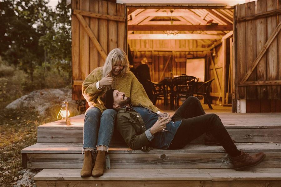 Ett par på en trappa framför en mysig lada.