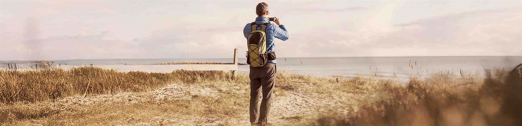 En man tar foton på en sandstrand.