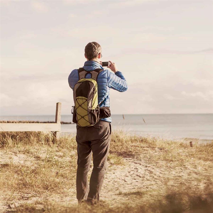 En man tar foton på en sandstrand.