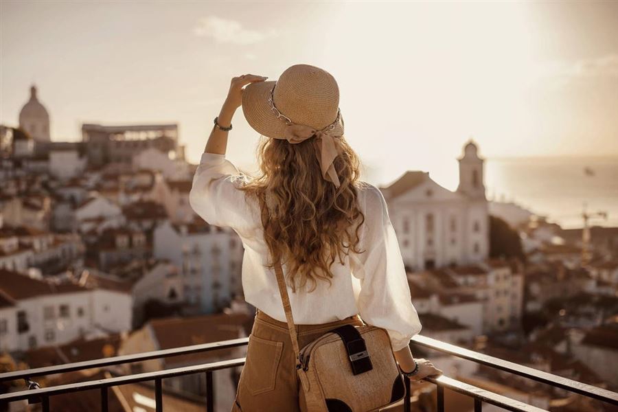 Kvinna blickar ut från en solig balkong.