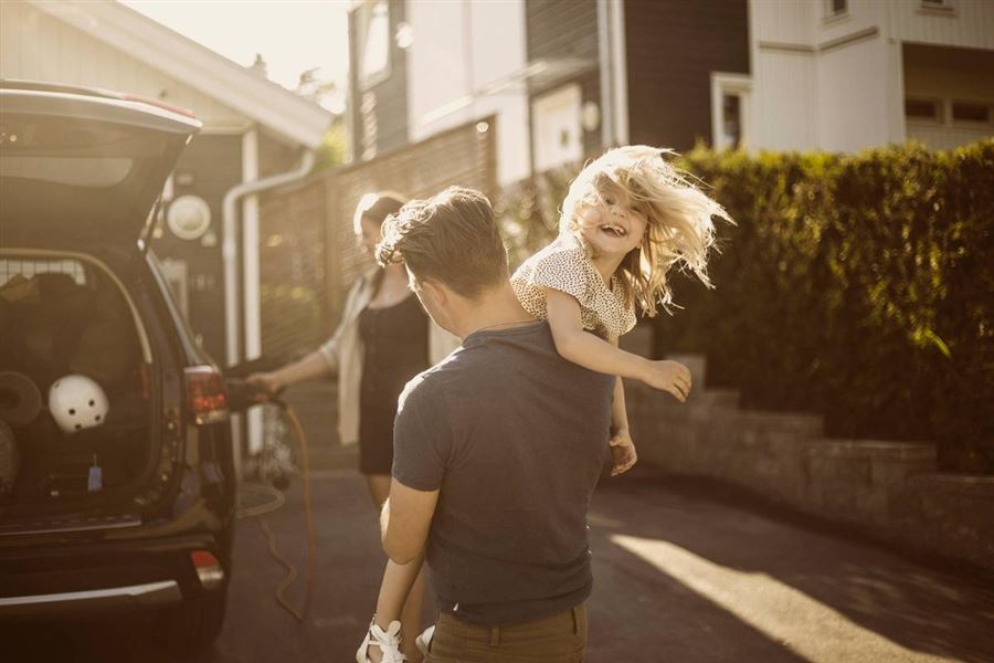 Pappa som bär sitt barn utanför ett hus.