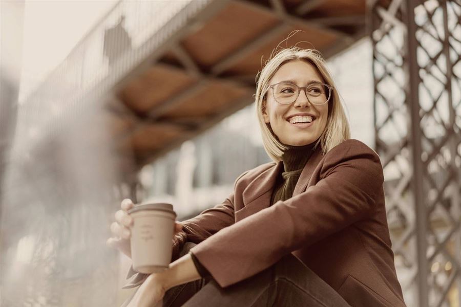 Kvinna som sitter ned utomhus med en kaffe.