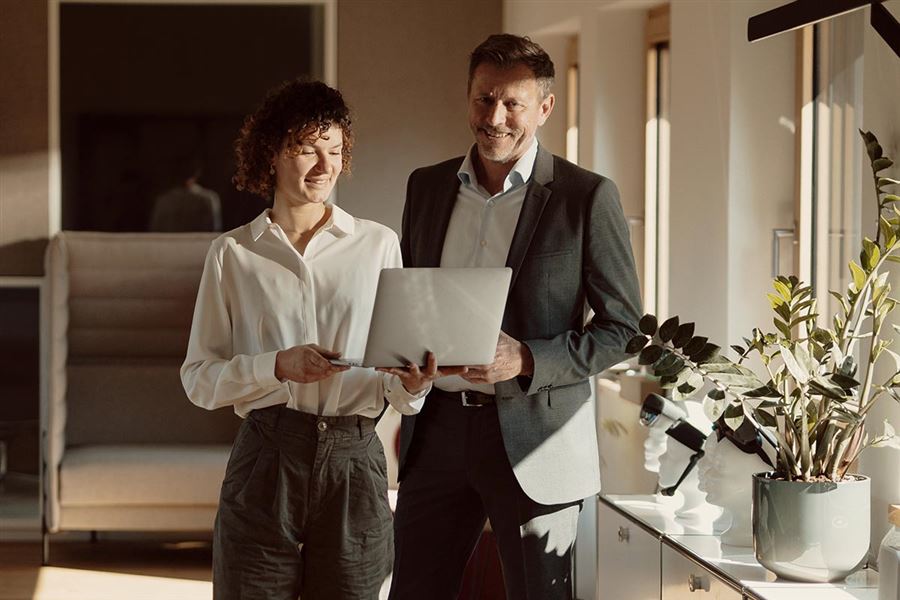 Man och kvinna diskuterar kapitalförvaltning och ser på datorskärm.